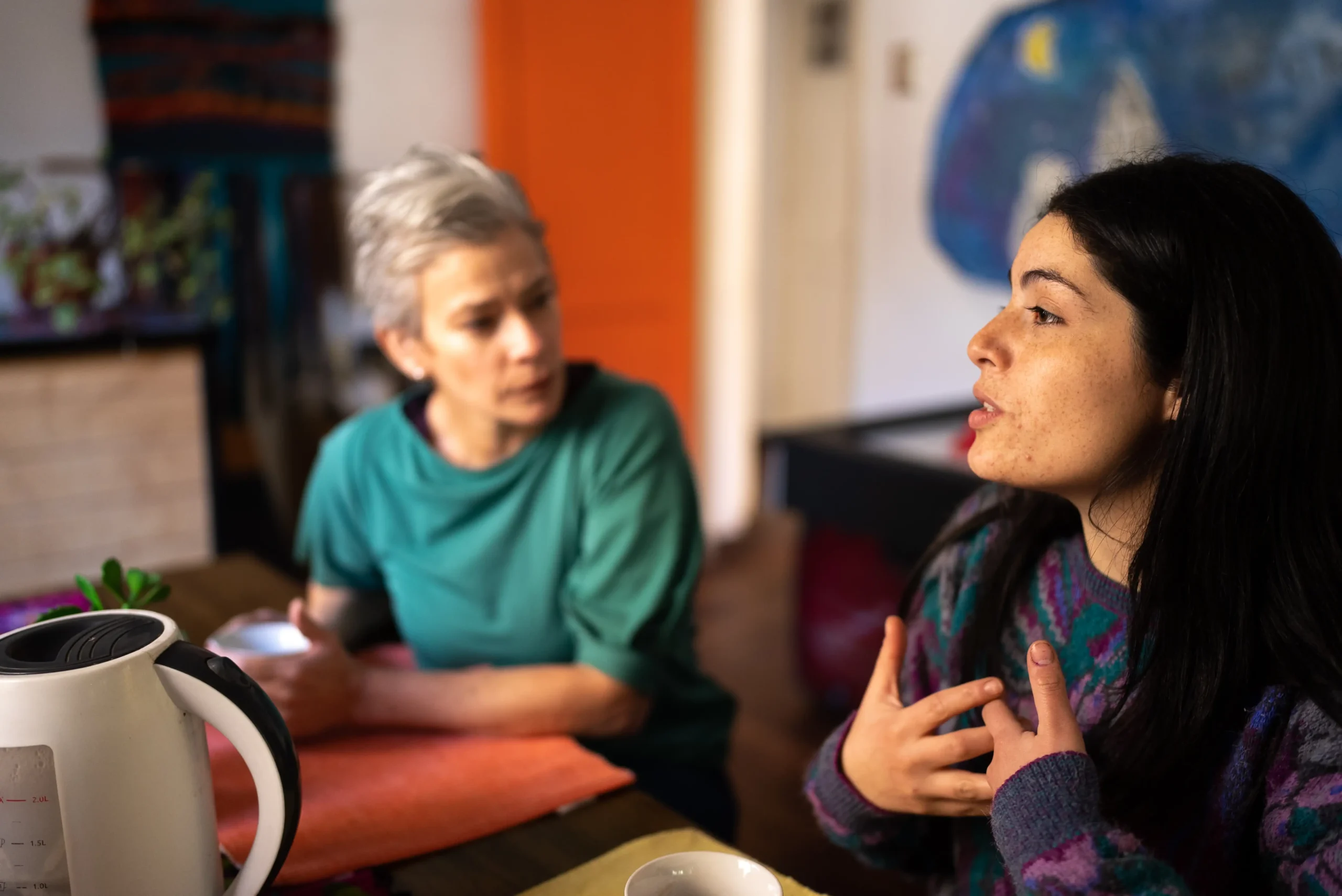 Mother and daughter talking while drinking coffee at home